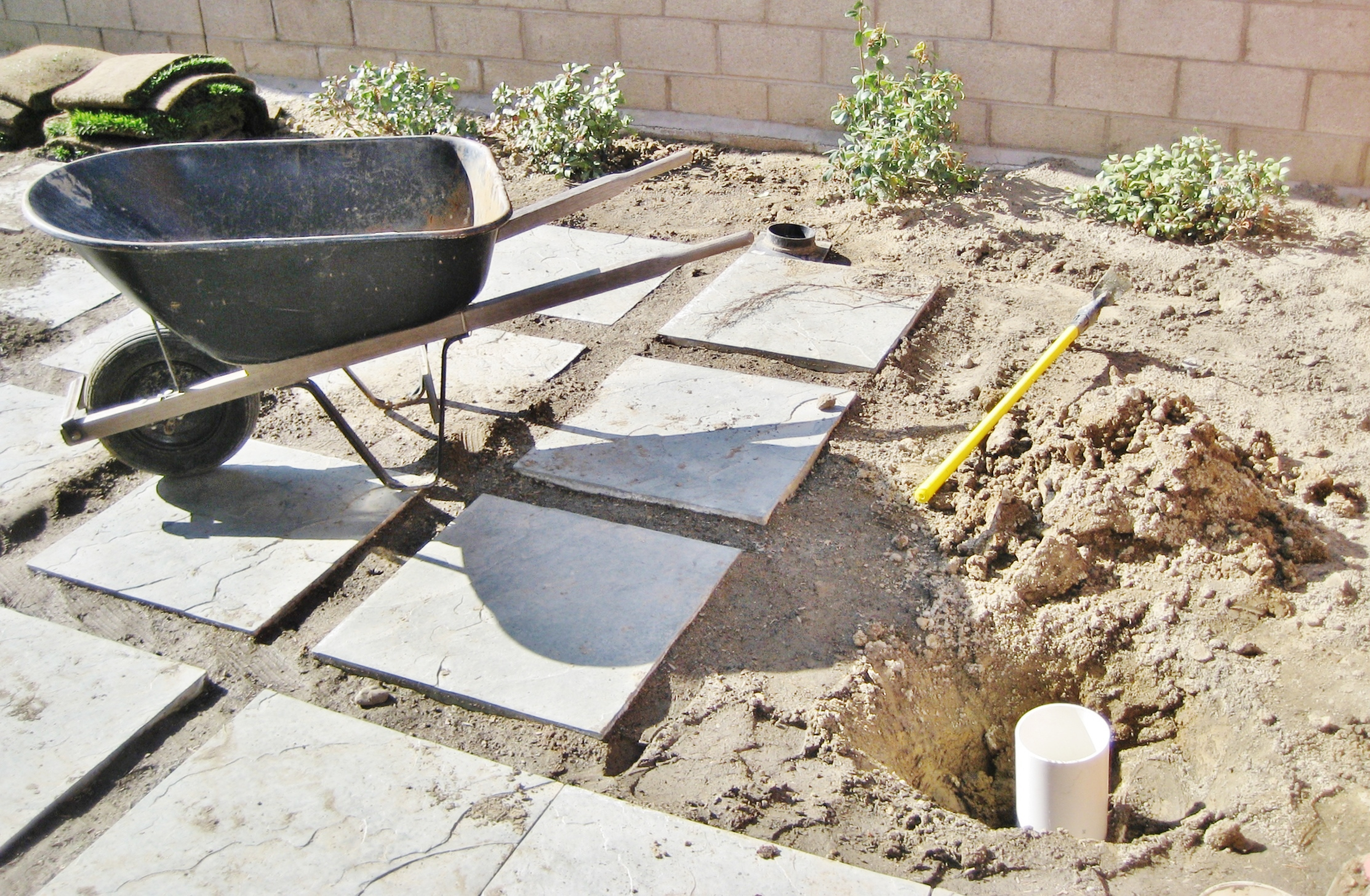 Backyard Construction process with Concrete Bocks, Wheelbarrow, Sod, and Drainage